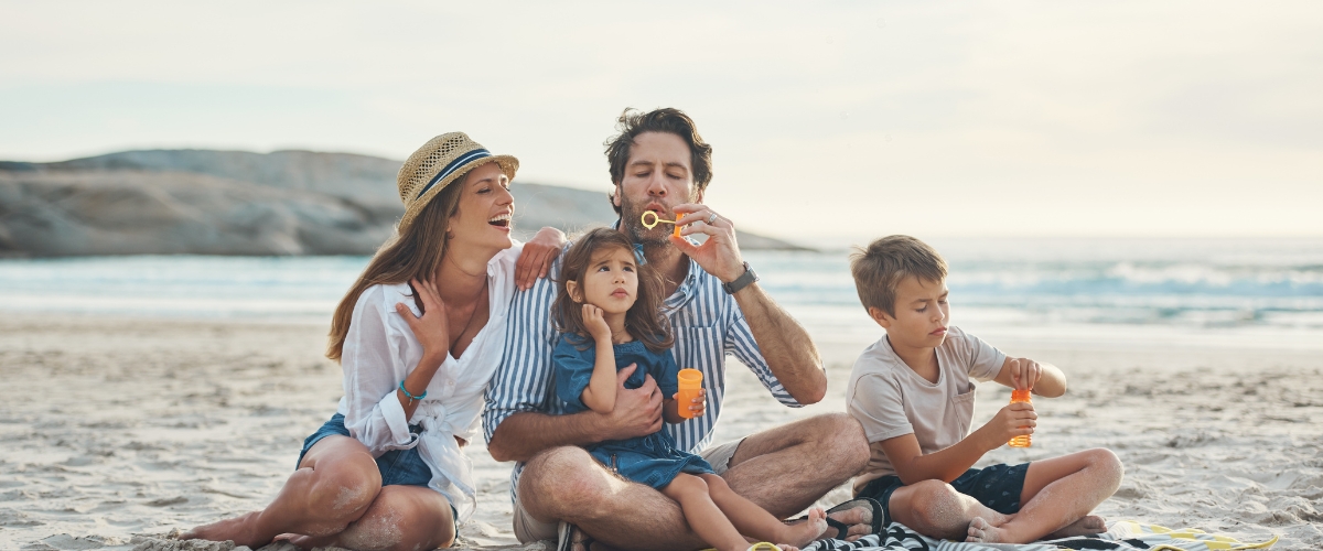 family sitting on the beach blowing bubbles