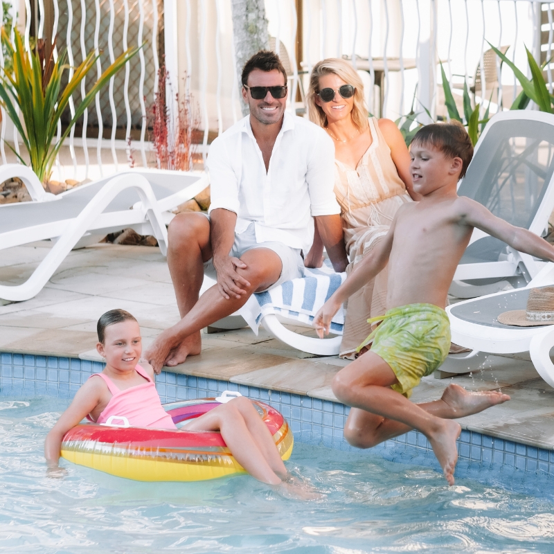 boy jumping into pool in front of family